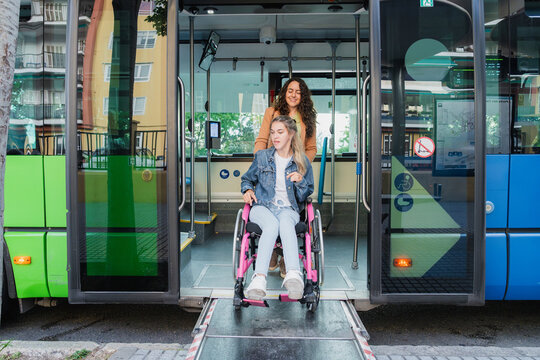 Caregiver pushes woman in wheelchair down public bus ramp