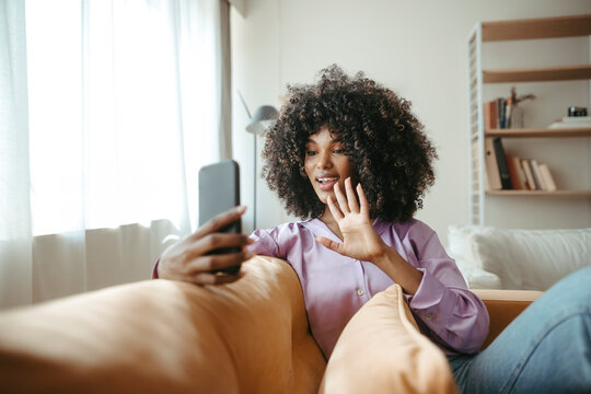 Woman waving on video call through smart phone at home