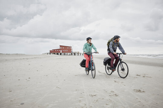 Germany, Schleswig-Holstein, St Peter-Ording, couple riding bicycle on the beach