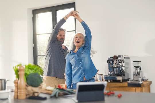 Youthful senior couple dancing in the kitchen