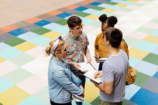 Students standing in backyrad, discussing, holding books