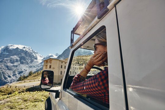 Woman looking through window of off-road vehicle on road trip, Passo dello Stelvio, South Tyrol, Italy