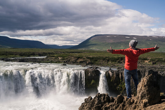 Man looking at Godafoss waterfalls, Iceland, with arms outstretched