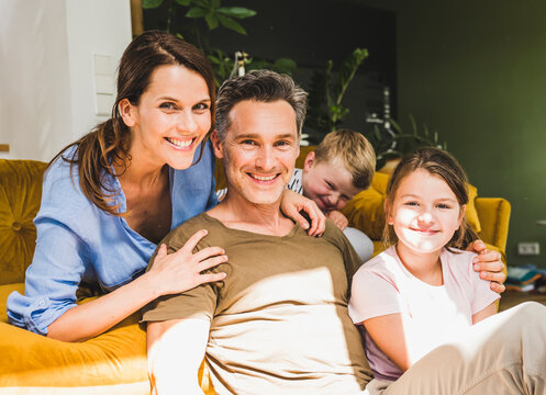 Man sitting with family near sofa at home during sunny day