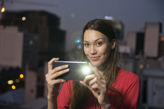 Young woman taking pictures of friends at a rooftop party