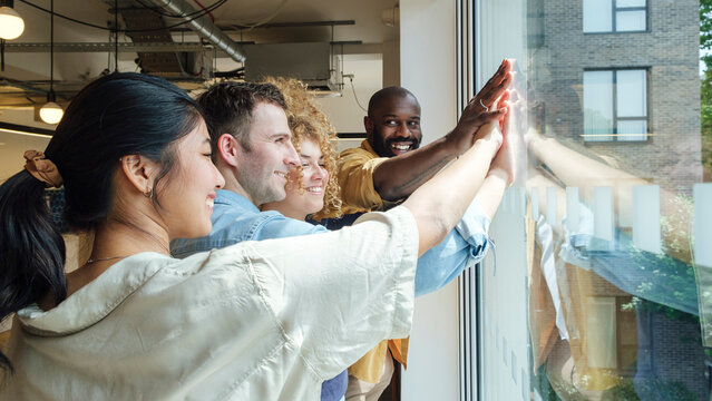 Group of business people looking out of window stacking hands
