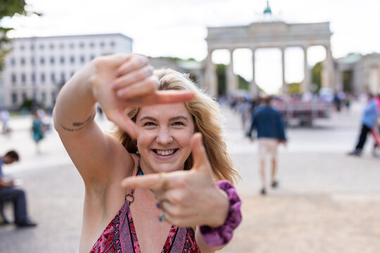 Smiling woman makes a frame gesture at Brandenburg Gate in Berlin