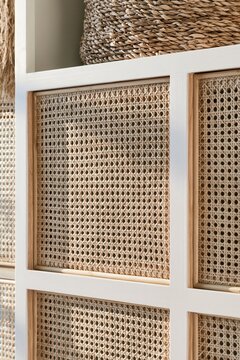 Closeup of woven rattan basket texture in a modern coastal wardrobe, showcasing natural fiber patterns illuminated by soft golden hour light