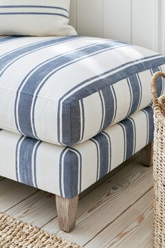 Closeup of navy-and-white striped linen upholstery on a coastal-style bench with natural wood legs and woven basket in a bright entryway