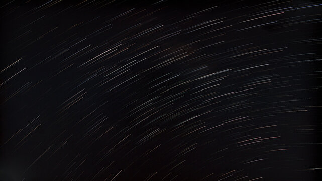 Circular star trails across a dark night sky captured with long exposure astrophotography, creating a dynamic celestial background.