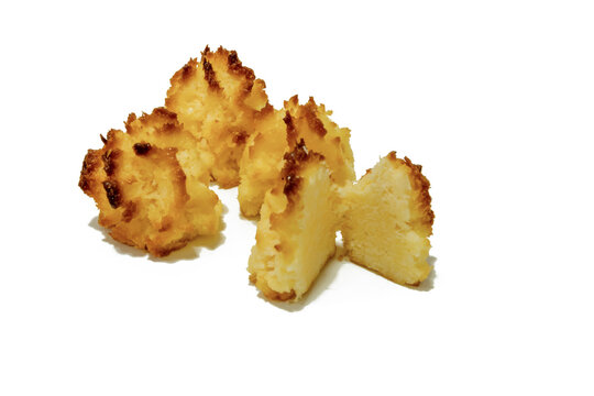Golden coconut macaroons with one cut open, isolated on white background. Homemade baked dessert for bakery, snack, recipe, gourmet food, menu, and food advertising.