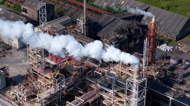 Close aerial view of industrial chemical plant with intricate pipework and smoke from chimney stack in Stallingborough, UK