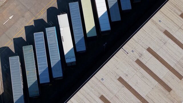 Close aerial view of HGV trucks and trailers parked at warehouse loading bays in distribution center