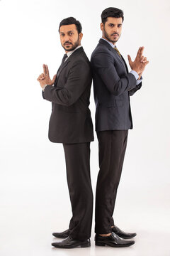 Two corporate employees in formal business suit Standing back to back adjacently making fingerguns.