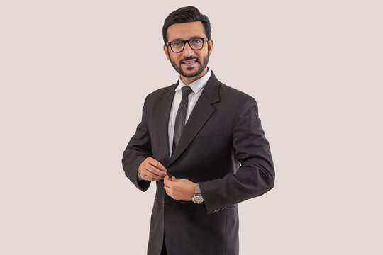 Portrait of a corporate employee in formal business suit standing while closing buttons of his jacket.