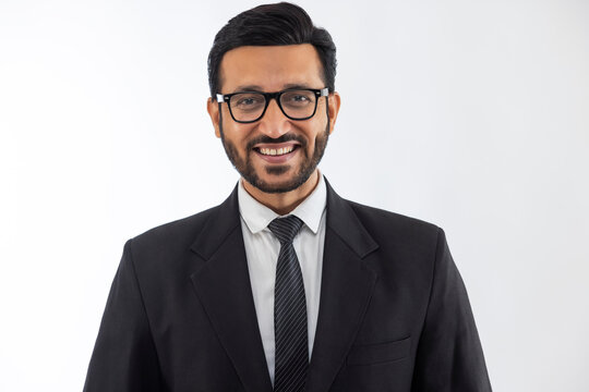 Portrait of a corporate employee in formal business suit smiling against plain backdrop.