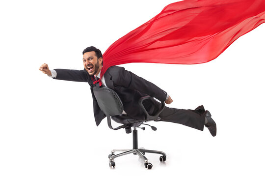 Corporate employee in formal business suit flying like superman lying on chair.