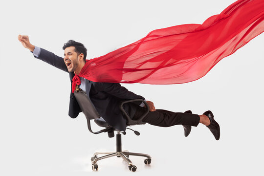 Corporate employee in formal business suit flying like superman lying on chair.