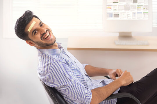 A corporate employee sitting in formal clothing smiling with blank stickynote on forehead.