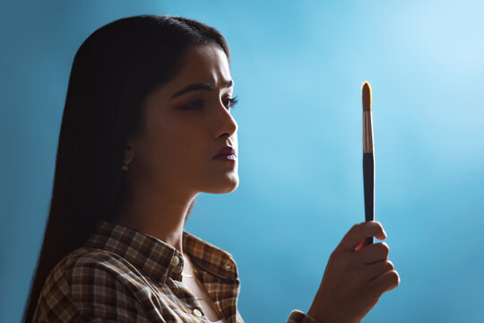Young artist girl holding brush and thinking for a new idea
