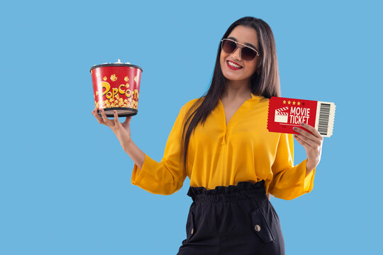 Young girl in black sunglass standing with movie ticket and popcorn
