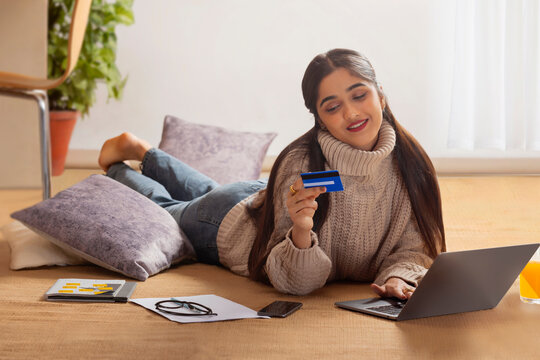 Smart young girl shopping online through laptop using debit card