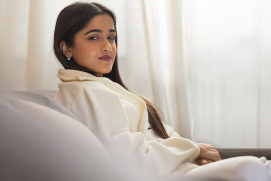 Girl looking at camera while sitting on sofa at home