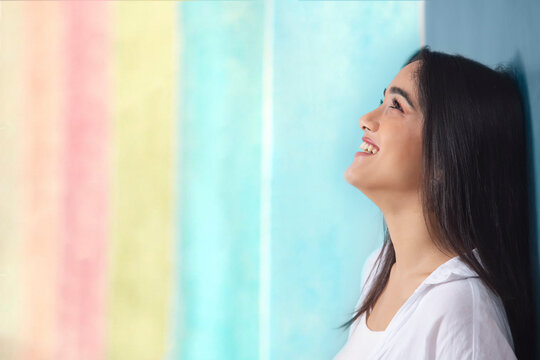 Close-up portrait of a young smiling girl against multicolored background