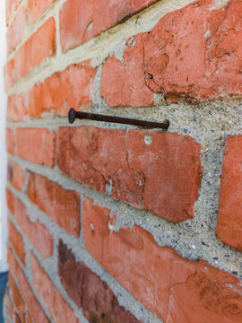 Red brick wall texture with old rusty metal nail