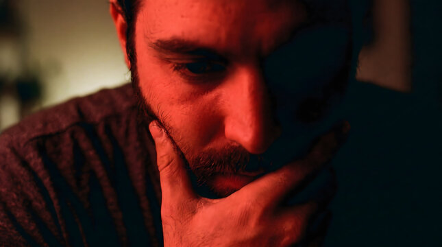 extreme close-up cinematic portrait of a handome and muscular male model, spanish indonesian man, face half-lit by deep red light, hand resting near his jaw and lips, eyes lowered, intense intimate 