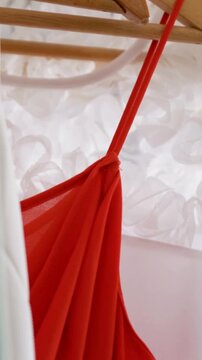 Vertical video: Camera filming red top revealing knot on hanger for detail, curtain, copy space