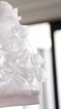 Vertical video: Shifting white ruffle panel rippling at window, light shifting by blurred panes