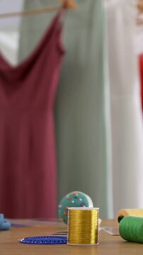 Vertical video: Tilting camera revealing maroon dress on hanger for display at studio, copy space