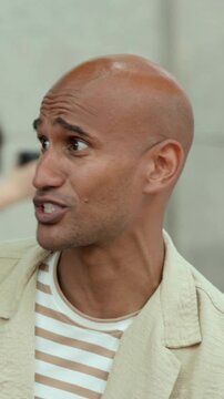 Vertical video: Reacting to offscreen voice man turning and speaking in lobby, wearing beige jacket