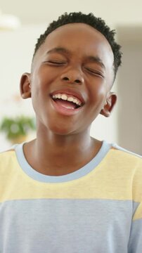 Vertical video: Framing boy in pastel-striped tee singing smiling laughing in home with plant
