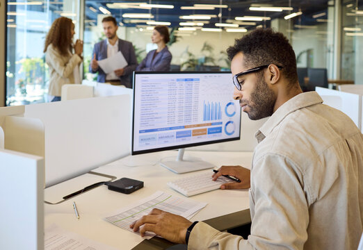 Analyst manager businessman reviewing spreadsheet charts on computer. The professional in a modern office reviews financial analytics and daily reporting. Clear concept of finance analytics.