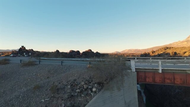 Deep basalt river canyon and rural road bridge in La Payunia Reserve. Fast, aerial FPV traverse on late afternoon sunset with clear skies.