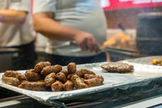 Freshly grilled chevapi and meat patty on a tray in a restaurant