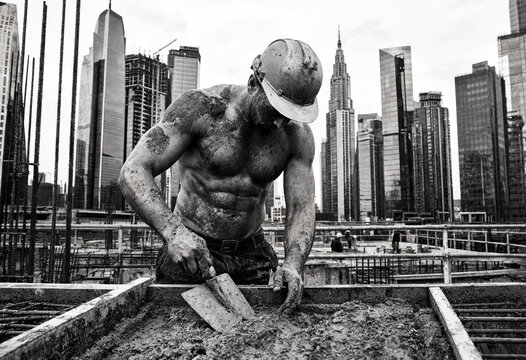 Shirtless Muscular Construction Worker in Hard Hat Working with Cement, City Skyline Background