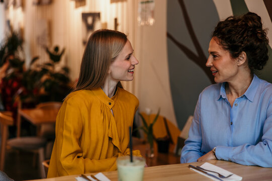 Women friends enjoying conversation and smiling in cafe