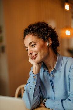 Woman smiling while working remotely with earbud headphones