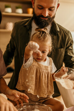 Daughter having fun baking with father in kitchen