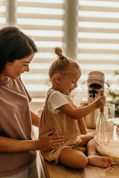 Mother and daughter baking together in kitchen, sharing joy