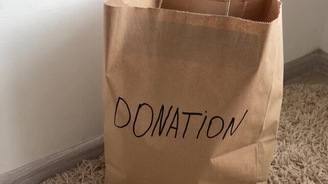 Donation bag filling with clothes for charity, showing a concept of kindness, secondhand giving, helping the needy, reusing items, and environmental responsibility