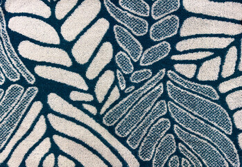 Close up of soft cloth fabric featuring a vibrant, abstract leaf pattern in striking deep teal blue and off-white tones. © TMR Studio
