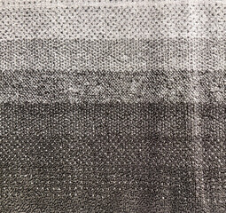 Close up of a soft woven terry towel featuring a textured gradient of horizontal color block stripes in black, charcoal, and grey. © TMR Studio