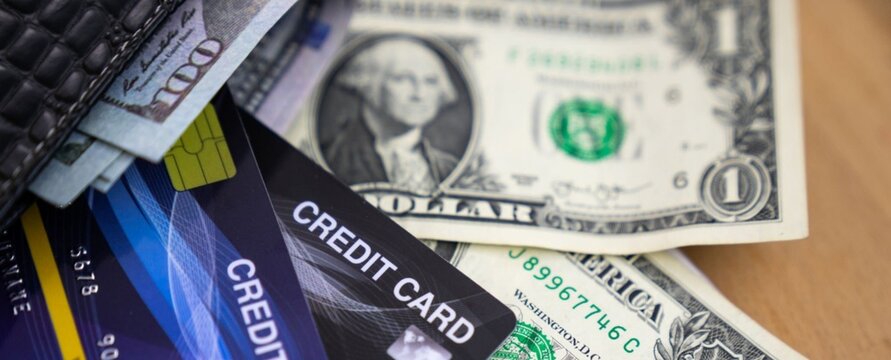 Money and cards lie scattered, a mix of cash and credit. Dollar bill and cards show everyday financial tools. No people are visible, so no emotions to describe. Perfect for budgeting, shopping