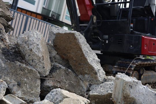 Heavy machinery grading concrete rubble and cement debris during residential road construction.