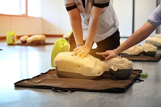 CPR training. Healthcare professional practicing CPR chest compressions on a medical dummy during first aid training session. Concept of emergency response, life-saving skill, and medical education.
