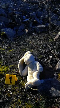 Chilling scene showing an abandoned stuffed bunny toy next to a yellow crime scene investigation marker number one, symbolizing the loss of childhood innocence and a potential child abduction